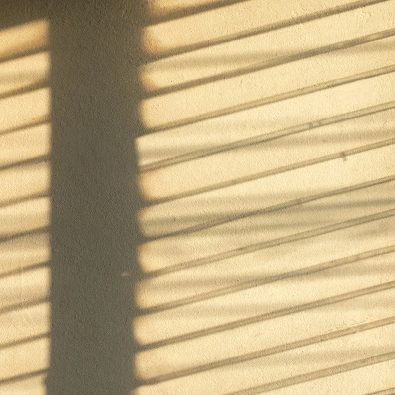 Lumière du soleil filtrée à travers un store, rayures d'ombre chaudes