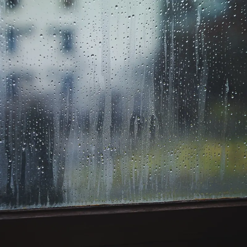 Gouttes de pluie sur une vitre, vue floutée sur l'extérieur